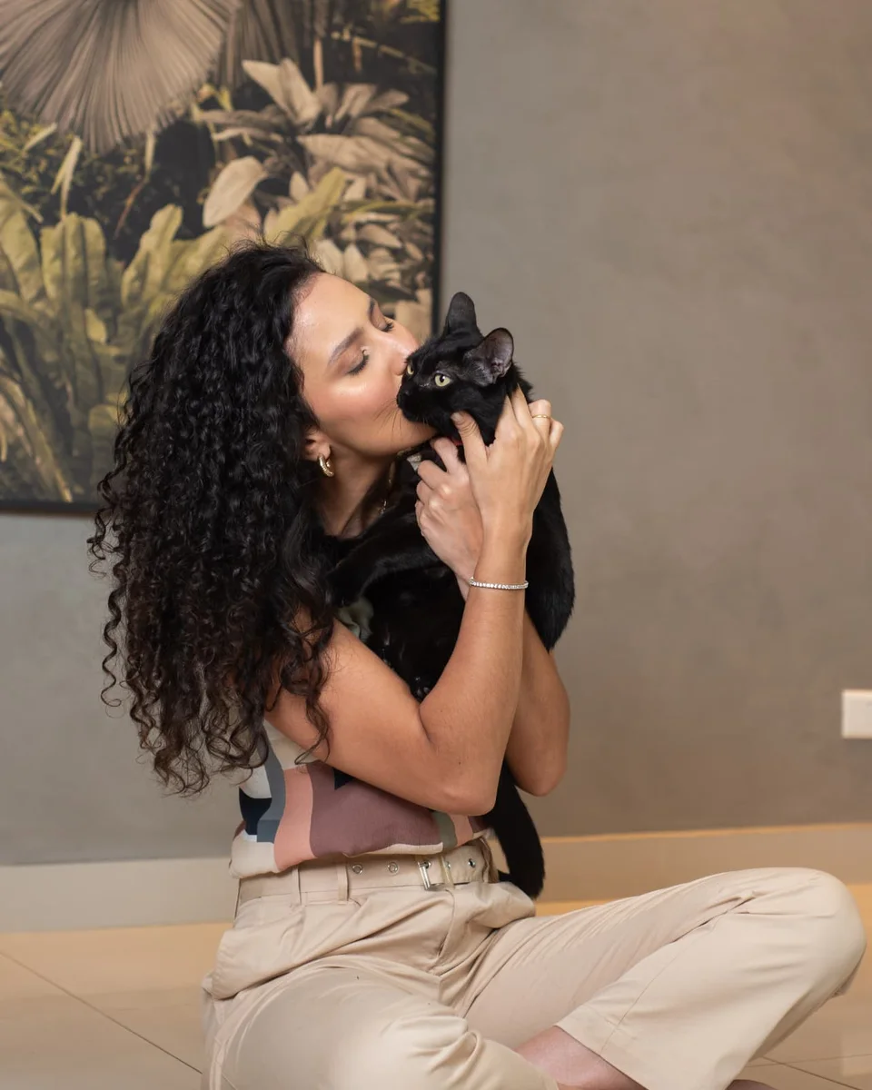 Sarah sentada no chão, abraçando sua gatinha