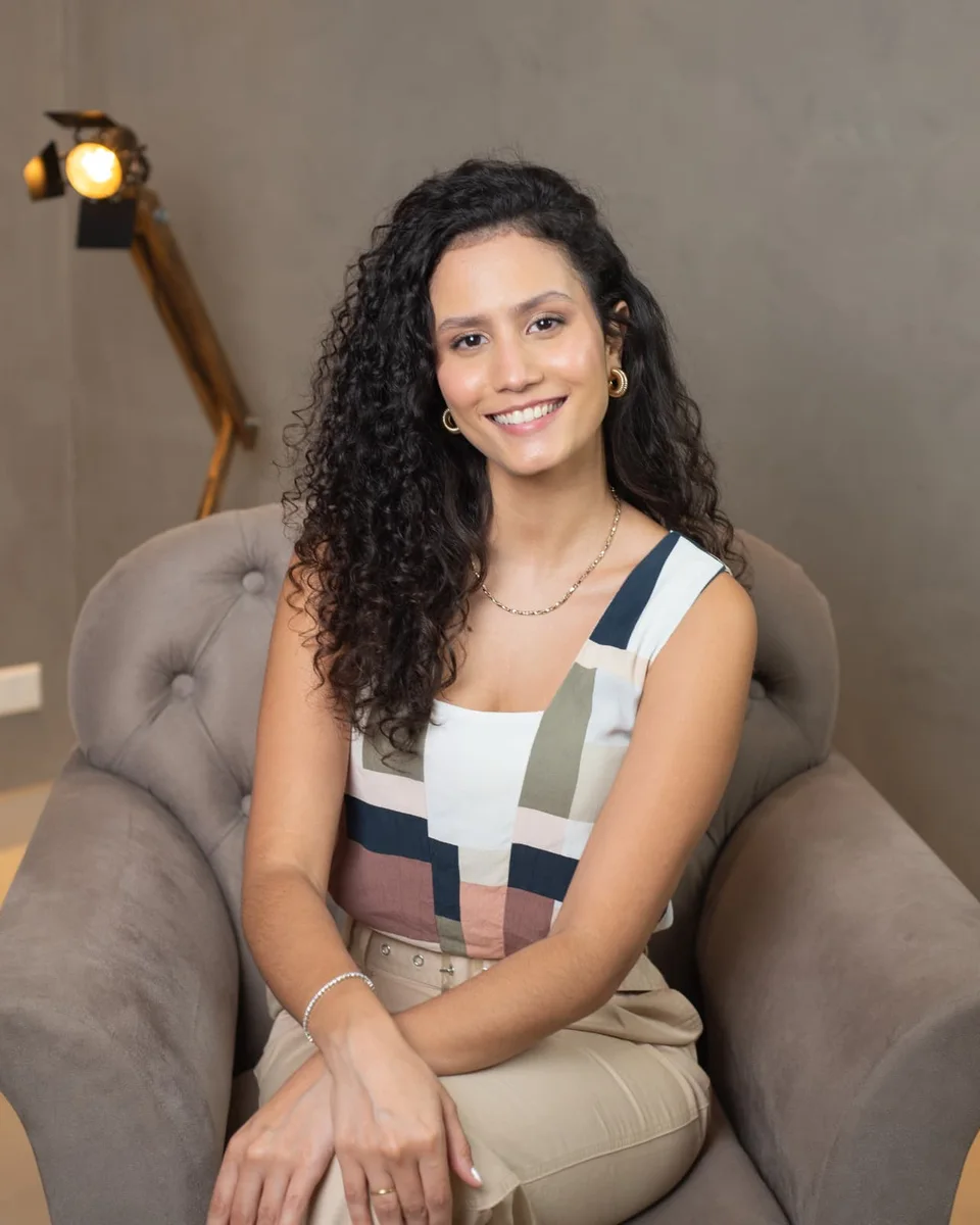Sarah, psicóloga, sorrindo sentada em uma poltrona
