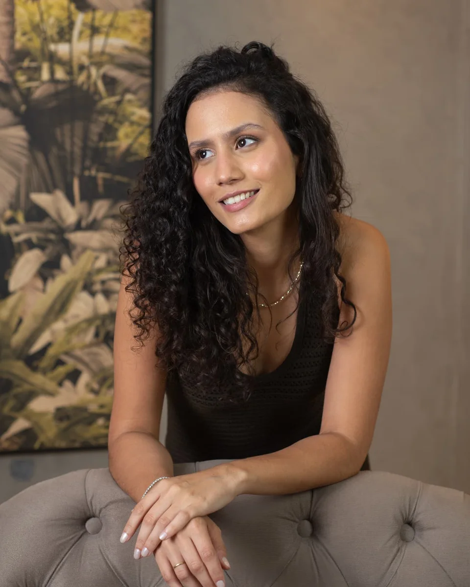 Sarah inclinada no encosto de um sofá, olhando para o lado